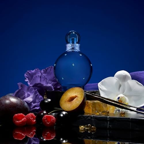 Blue perfume bottle with floral and fruity arrangement, featuring plums, raspberries, and orchids against a deep blue background.