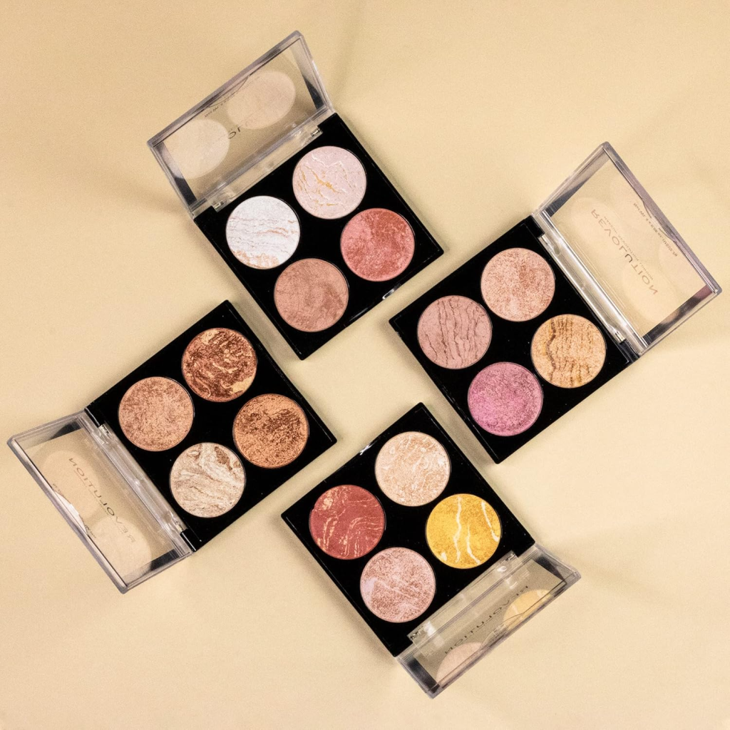 Four open makeup palettes showcasing a variety of shimmering highlighter shades on a beige background.