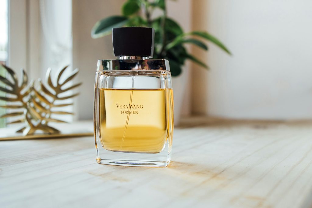 Men's perfume bottle on a wooden table with green plant in background, elegant fragrance packaging